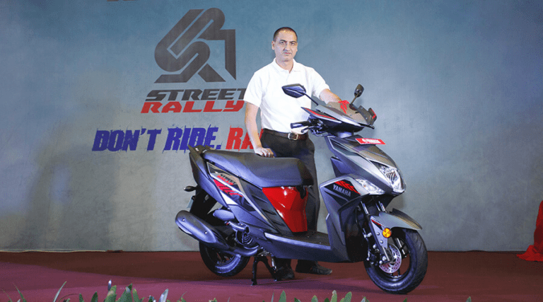 Man presenting a new scooter model at a launch event.
