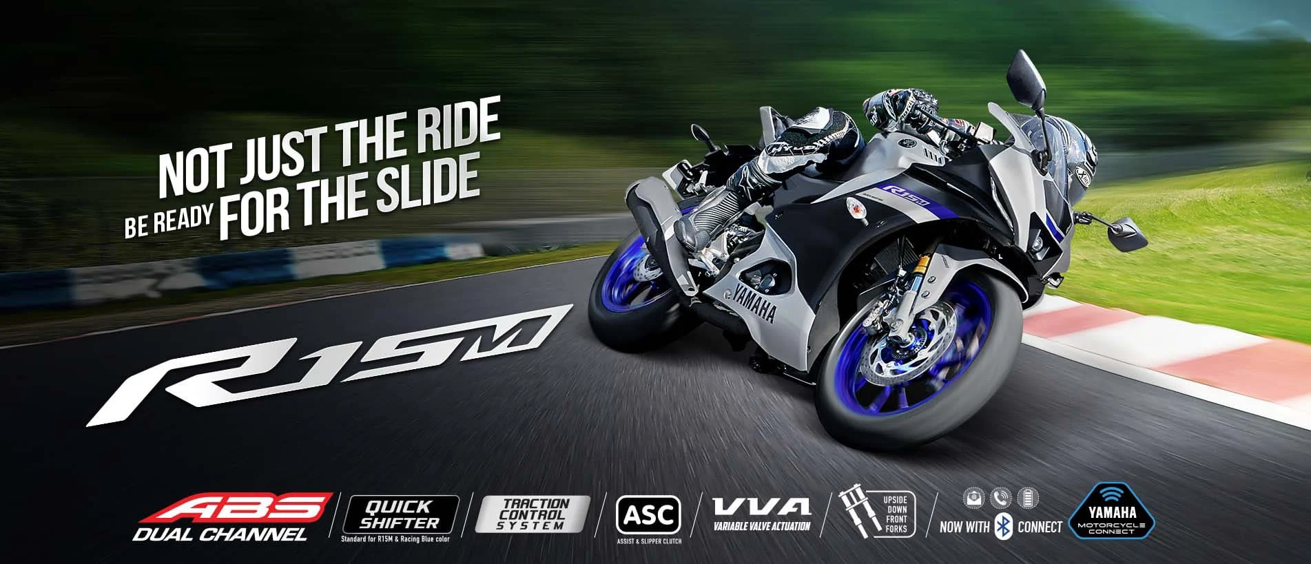 Yamaha R15M motorcycle in motion on a racetrack with a rider in full gear.